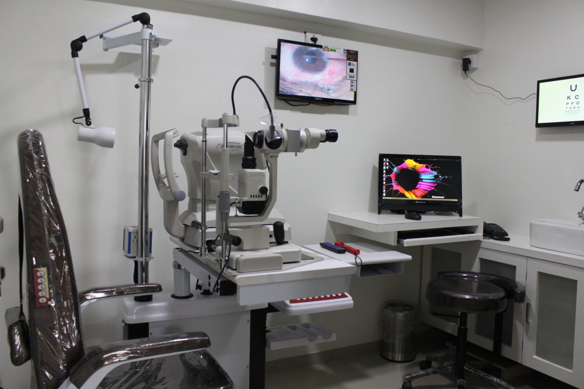 Slit-lamp anterior-segment imaging chamber at Insight Institute with patient chair, hand-rest control, live keratometry image and ophthalmic chart screens